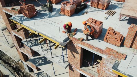 Aerial view Builders working on construction and laying bricks. Bricklaying of a brick multi-storey building