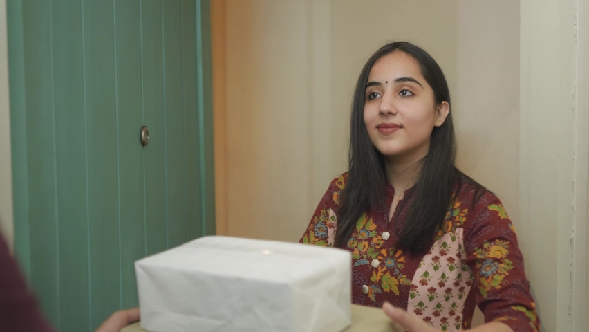Close shot of beautiful young Indian woman in traditional salwar kurta receives the parcel delivered at the doorstep of her apartment or residence by a delivery man and closes the door thereafter | Shutterstock HD Video #1070849164