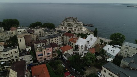 Aerial view of houses by the sea with iconic building on the seafront and large ships in the far distance, Drone view of city buildings near the sea