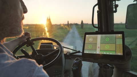 farmer male driving tractor uses smart display touch screen application to check the fields of the farm,agriculture new technology app onboard of agricultural machine,modern farmhouse startup