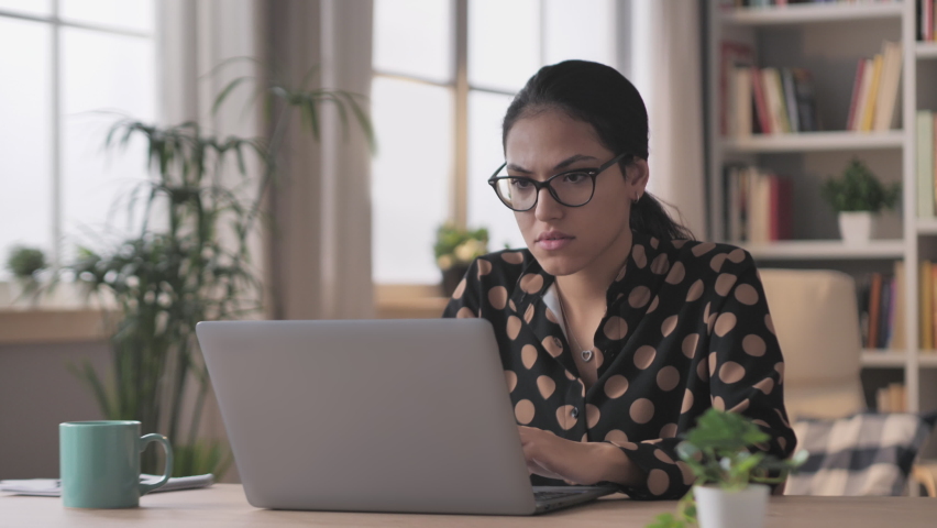 Angry business woman sits at the desk works from home at the laptop burst in rage,arab female businesswoman working at the computer feels furious stressed,having problems at work | Shutterstock HD Video #1070854891