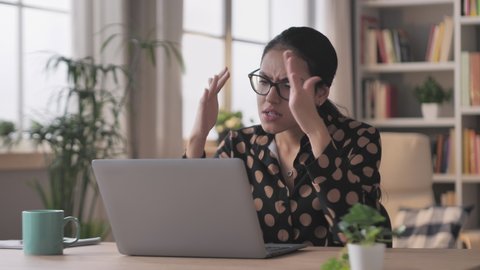 angry business woman sits at the desk works from home at the laptop burst in rage,arab female businesswoman working at the computer feels furious stressed,having problems at work