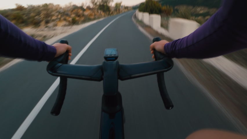 POV action shot of professional cyclist descend down steep dangerous mountain road.Cyclist in long sleeve jersey on carbon aero bike with integrated handlebar and computer ride very fast on empty road Royalty-Free Stock Footage #1070855614
