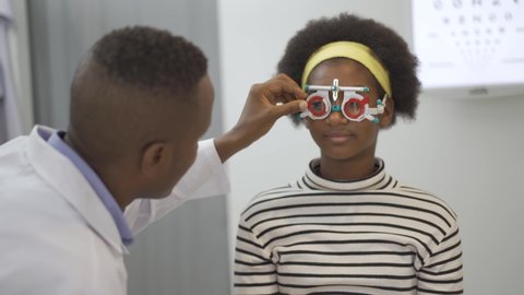 Smiling young woman african american checking vision with eye test glasses during a medical examination at the ophthalmological office, Checking eye vision by optician health examination concept
