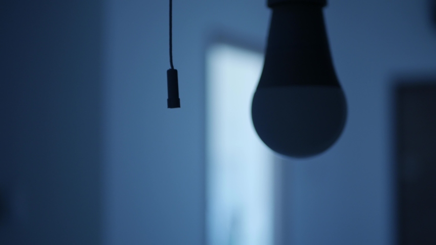 One Person Pull the Switch Cord and Turns On the Light Bulb in a Dark Room. Turning On a Led Light in the Office Room. Royalty-Free Stock Footage #1070864797