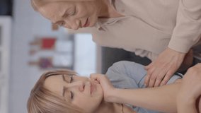 Pretty old woman soothing adult stressed daughter sitting together on sofa.Compassionate middle-aged mother supporting her depressed daughter at home.Video for the vertical story.