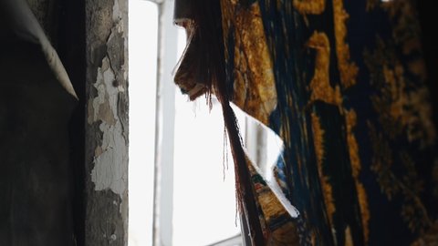 An old ragged cloth hangs over the window and stirs in the wind. Shooting in an abandoned house. Close-up