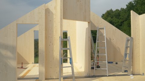 CLOSE UP: Contemporary glued-laminated timber house is being built in countryside. Aluminum ladders are scattered around the top floor of a CLT house under construction. Hardwood real estate project.