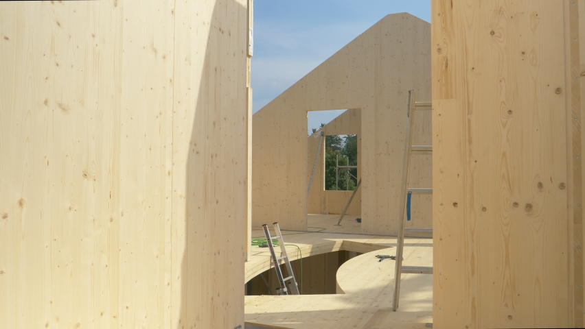 CLOSE UP: Beautiful hardwood real estate project is erected in the countryside. Glued-laminated timber house is being built in countryside. Aluminum ladders lie around the CLT house under construction | Shutterstock HD Video #1070869228