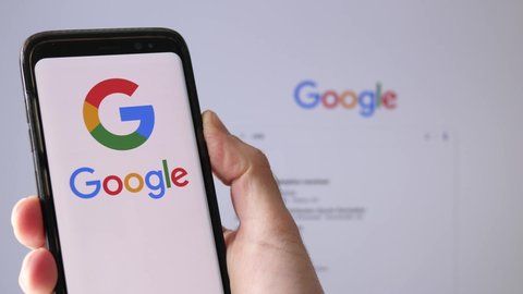 Google search logo on a smartphone and on the background the website on a computer monitor.MONTREAL CANADA APRIL 2021