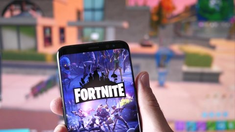 Fortnite game logo on a smartphone and on the background the website on a computer monitor.MONTREAL CANADA APRIL 2021