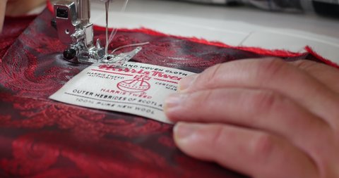 Hebrides, Scotland, United Kingdom Tailor machine sewing Hebrides Harris Tweed Brand label. Clothing and accessories in wool by Harris Tweed, classic wedding suit for the groom Harris Tweed wedding