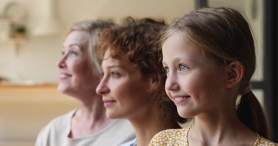 Profile faces in row three generation of women turn heads smiling looking at camera, close up. 60s grandmother, grown up daughter and little granddaughter. Multi-generational family portraits concept Royalty-Free Stock Footage #1070885611