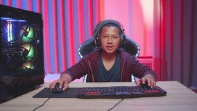 Asian Boy Wearing Headphones Playing Video Game, Laughing While Playing Video Game
