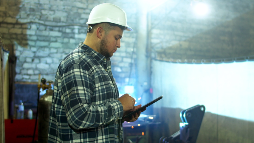 Plump male employee using tablet in factory workshop
