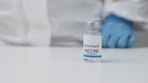 Sputnik V vaccine against coronavirus and syringe for injection in health worker hand in rubber gloves and protective suit, March 2021, San Francisco, USA