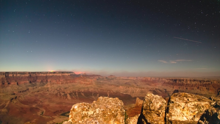 Star trails over the Grand Canyon south rim. Wildfire can be seen at the horizon.