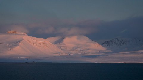 view of the Arctic mountains on the Spitsbergen archipelago. sunrise or sunset at Svalbard, Norway. timelapse video. Clouds swirl over the peaks. The wind blows the overcast. Northern winter landscape