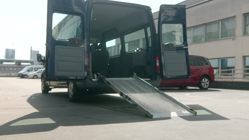 Assistant helping disabled person on wheelchair with transport using accessible vehicle ramp Royalty-Free Stock Footage #1070907541