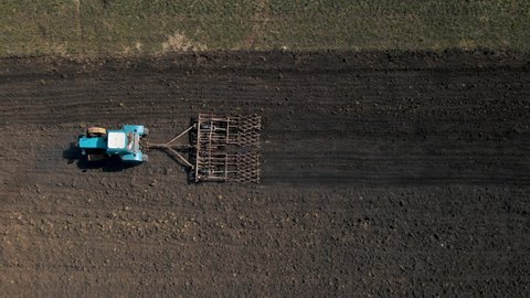 Aerial top view of one tractor dragging a disc harrow or a seedbed cultivator, soil, planting new wheat crop. Agriculture concept. tractor works in the field.