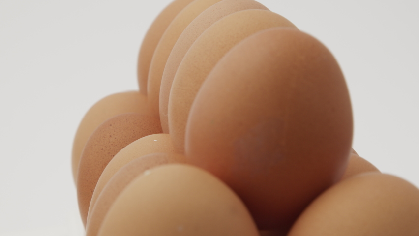 Eggs in a cardboard box, rotation shot, Chicken white fresh raw eggs in an egg container. Egg Box With Eggs On white Table Panning. Open egg box with ten brown eggs. Many fresh raw chicken egg Royalty-Free Stock Footage #1070924326