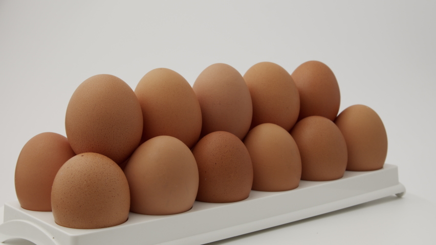 Eggs in a cardboard box, rotation shot, Chicken white fresh raw eggs in an egg container. Egg Box With Eggs On white Table Panning. Open egg box with ten brown eggs. Many fresh raw chicken egg Royalty-Free Stock Footage #1070924365