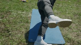 Playful sportsman extends leg behind him on fitness mat in the park