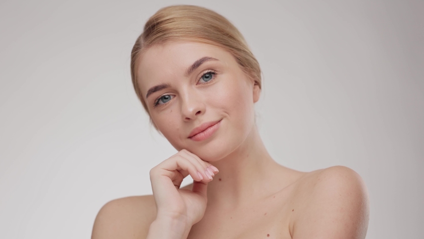 Woman model with fresh skin, white smile and natural facial makeup portrait on light background. Close up portrait young beautiful blonde girl. Female look at the camera and smiling. Beauty.