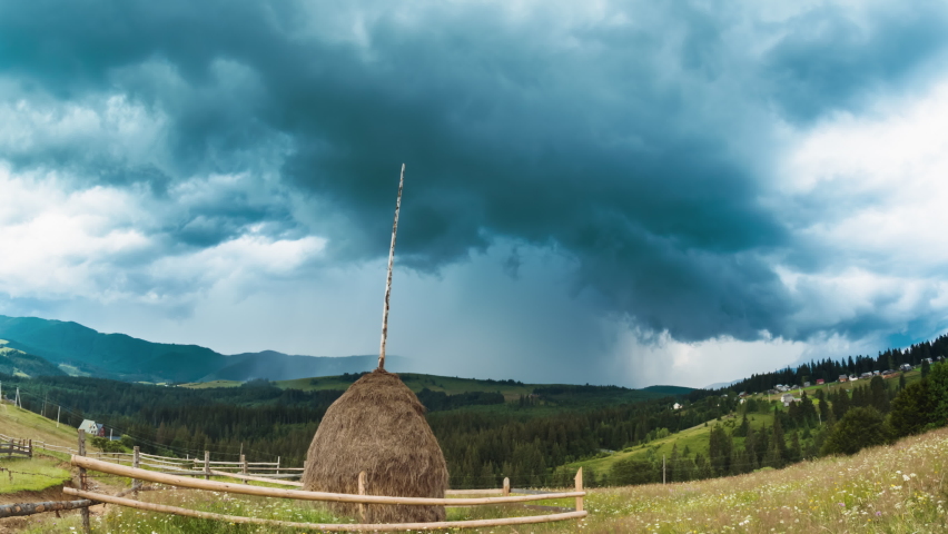 Time lapse of dark dramatic stormy clouds with rain and thunderstorm passing by summer mountains landscape. Rain drops on lens.