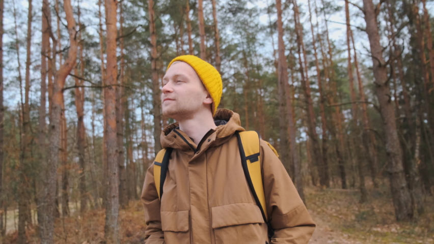Young happy beautiful male smiling standing on the forest road. Travelling.