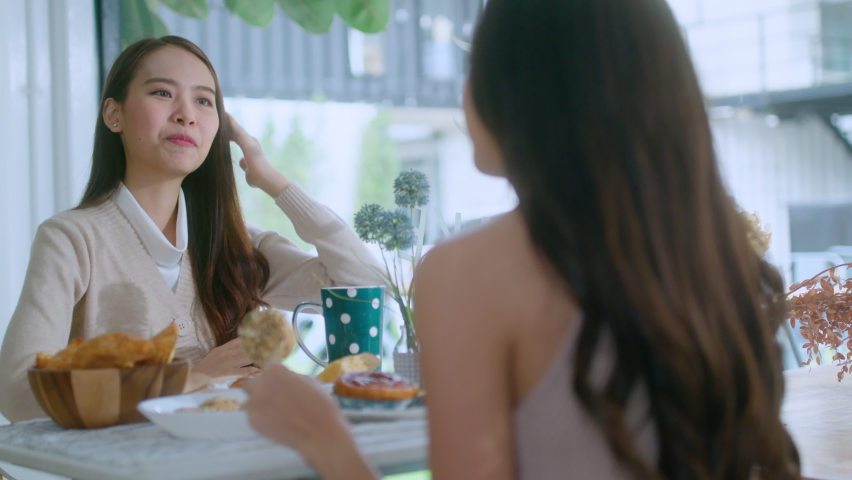 attractive asian female talking good positive conversation to friends with smiling laugh and happiness moment at counter near window at cafe with daylight from garden positive attitude relationship