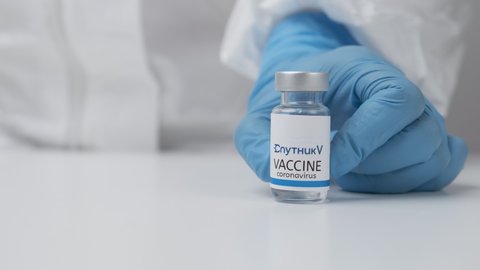 Sputnik V vaccine against coronavirus and syringe for injection in health worker hand in rubber gloves and protective suit, March 2021, San Francisco, USA