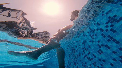 Underwater view of woman's legs swinging in a pool