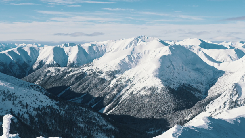 Snowy landscape in the winter season. Snow-covered mountains against the cloudy sky. High quality 4k footage