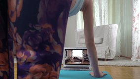 Young beautiful fit woman following yoga online video tutorial in her living room dining quarantine restrictions. Yoga, pilates, working out exercising
