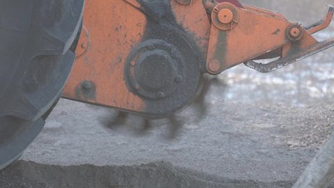 Saw for cutting asphalt mounted on a tractor. Road milling machine cuts the old asphalt. Road repair. Destruction of the road surface. The cutter cuts a layer of asphalt. Pieces of stone fly apart. 