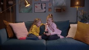 At Home Sitting on a sofa: Cute Little Girls surf the page, like picture and posting new story, Playing in Competitive Video Game on Smartphone, Holding them in Vertical Landscape Mode. 