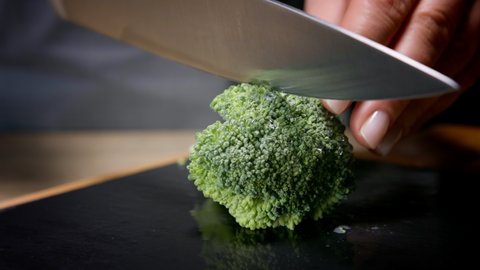 Female hands cut broccoli florets in half. Macro shot, 150 fps, slow motion. 