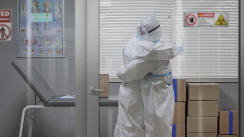 Coronavirus pandemic,health care workers in protective suit mask embrace hug in hospital room,covid-19 epidemic,medical personnel staff are embracing hugging,comfort each other
