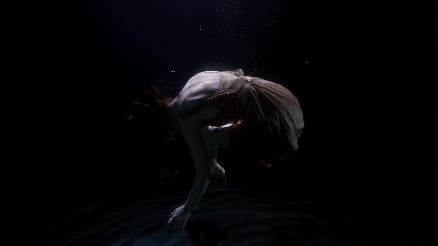 female body underwater, curled up woman is lowering on bottom of sea or ocean Royalty-Free Stock Footage #1070971915