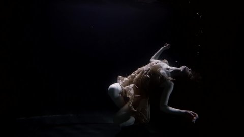 female corpse is sinking inside sea or river, underwater shot of woman figure in darkness and deepness