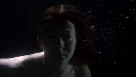 mysterious naked woman is floating underwater, closeup portrait