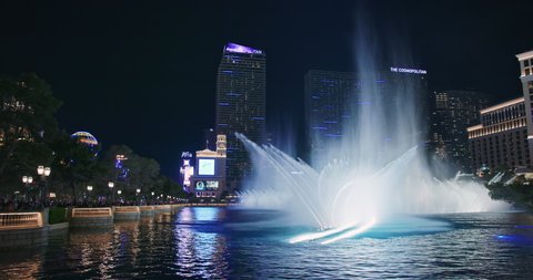 Las Vegas, USA, March 2021. Beautiful night scene, impressive Fountains at Bellagio Casino with Cosmopolitan hotel building on background. World famous free night shows on Las Vegas Strip. footage 4K
