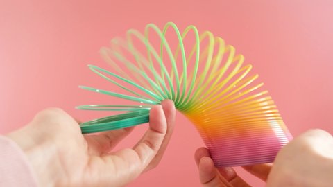 Plastic rainbow toy in hands. Colored spiral for games and tricks popular in the 90s. Minimalism. The concept of toys, childhood. brightness.