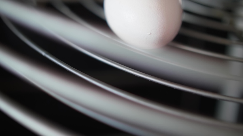 White boiled egg is on plate. Hand takes it. Close up view.