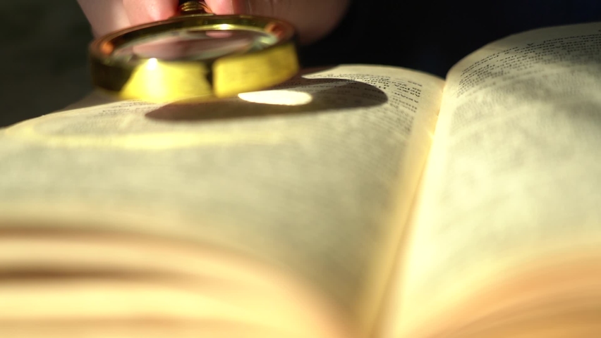 Close-up Hand with a magnifying glass and an old book. Knowledge accumulation and history concept