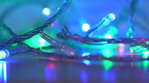 Closeup 4k stock video footage of bright colourful vivid garland holiday lights shining and glowing in darkness. Christmas decorations