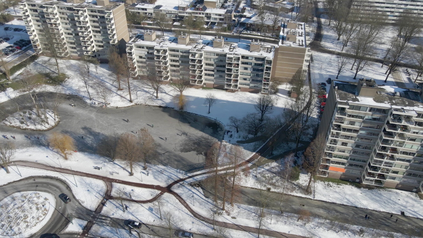 Aerial dolly of people skating on frozen pond in a small Dutch city in the Netherlands