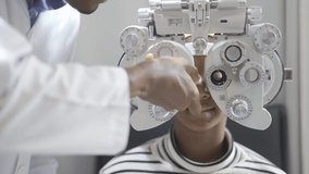 Optician doing optometry eye exam for black african american teen girl patient. Male optometrist with phoropter while examining patient. - Powered by Shutterstock - Get 15% off with code: PIKWIZARD15
