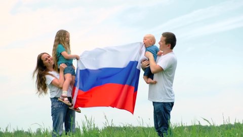4k. Happy family mother father and two kids girl and little boy waving national Russia flag outdoors green grass blue sky at summer - russian flag, country, patriotism, Russia day and 12th june